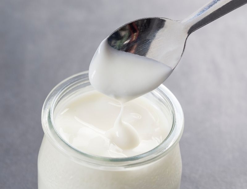 Thick and creamy homemade yogurt in a jar with a spoon